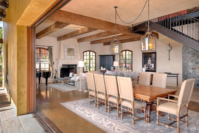 dining room with beam ceiling, finished concrete floors, and a fireplace