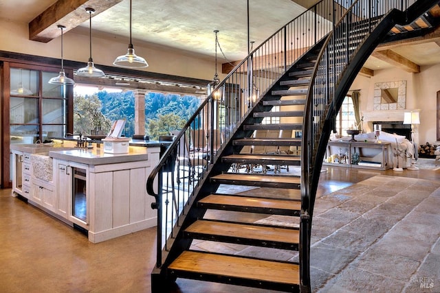 staircase with a fireplace, beverage cooler, and beam ceiling