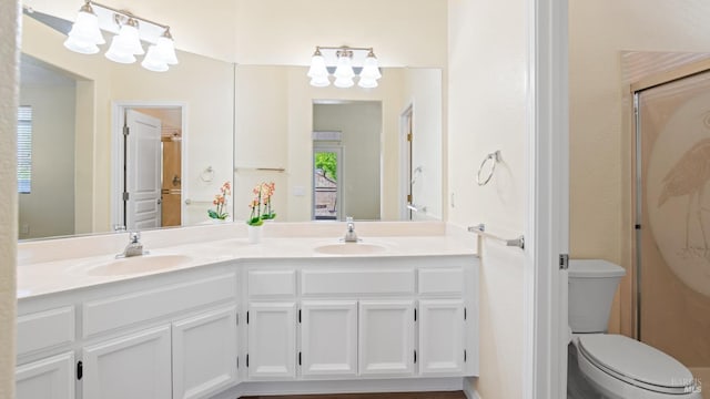 full bath with double vanity, a sink, toilet, and a notable chandelier