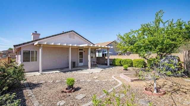 back of house featuring stucco siding, a chimney, a fenced backyard, and a patio area