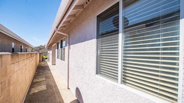 view of side of home featuring stucco siding and fence