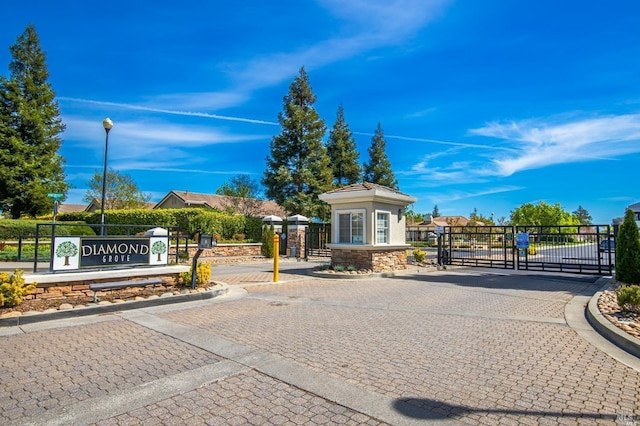 view of road with street lights, a gated entry, a gate, and curbs