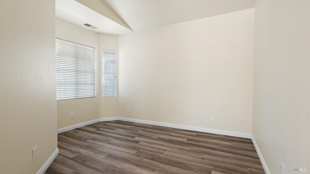 spare room with dark wood-type flooring, baseboards, and visible vents