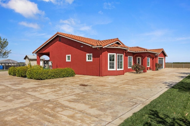 19810 S Spruce Rd, Los Banos, CA 93635 - view of side of home with a tiled roof, driveway, an attached garage, and stucco siding
