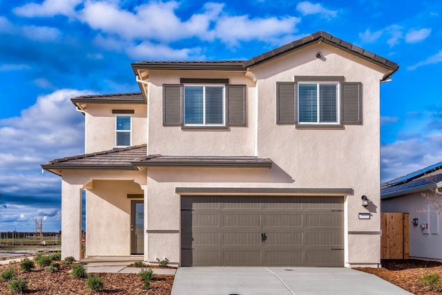 view of front facade with a tiled roof, driveway, stucco siding, and an attached garage