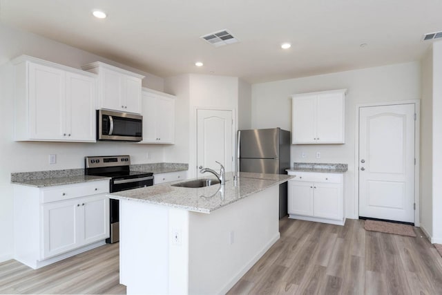 kitchen with light wood-style flooring, stainless steel appliances, a sink, visible vents, and white cabinets