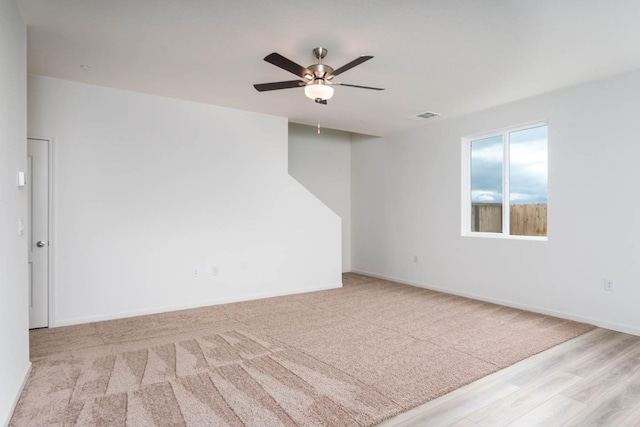 spare room featuring a ceiling fan, wood finished floors, baseboards, and visible vents