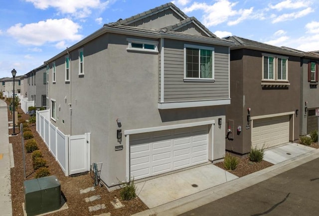 view of front facade featuring stucco siding, an attached garage, fence, and concrete driveway