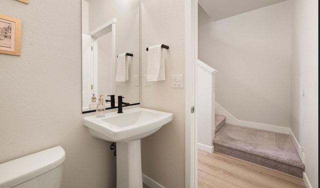 half bath featuring toilet, baseboards, and wood finished floors