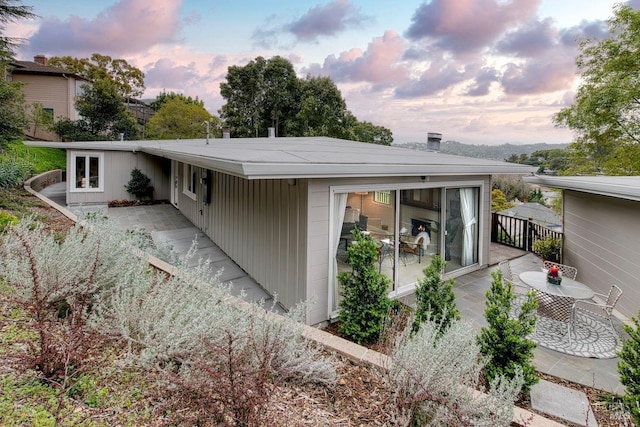 back of house at dusk featuring a patio area