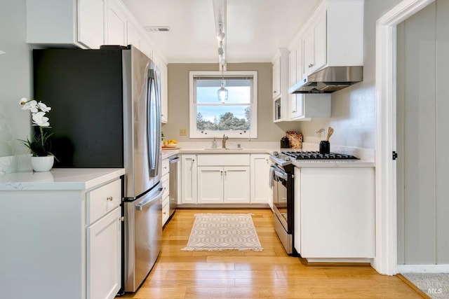 kitchen with white cabinetry, light wood-type flooring, stainless steel appliances, under cabinet range hood, and visible vents