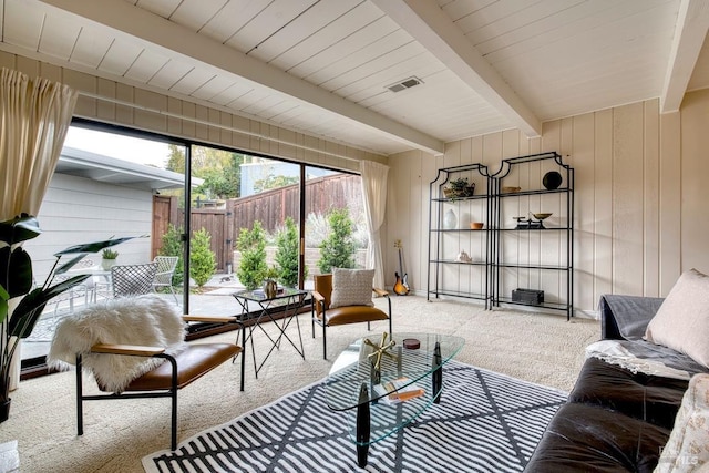 living room featuring visible vents, light carpet, wooden walls, and beam ceiling