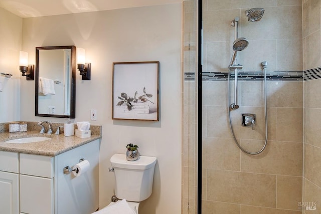 full bath with a tile shower, toilet, and vanity