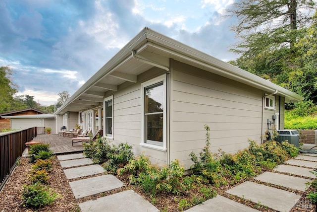 view of home's exterior featuring central air condition unit, a wooden deck, and fence
