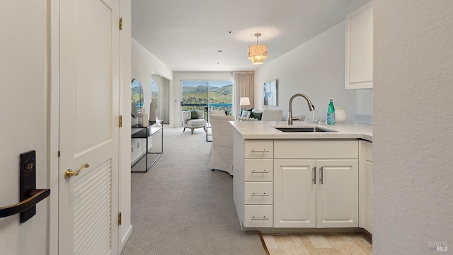 kitchen with a peninsula, light countertops, white cabinets, and a sink