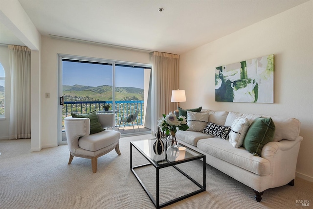 living room featuring a mountain view, baseboards, and light carpet
