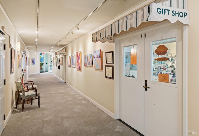 corridor with track lighting, carpet, and baseboards