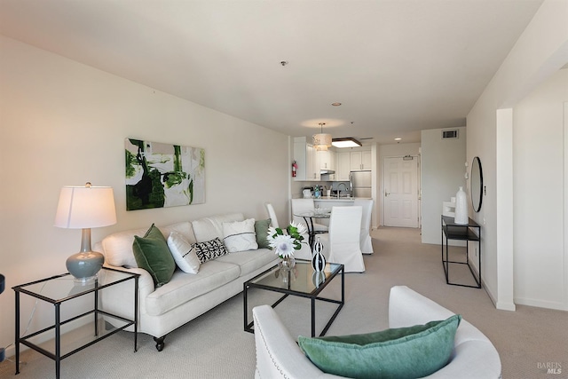 living area with baseboards, visible vents, and light colored carpet