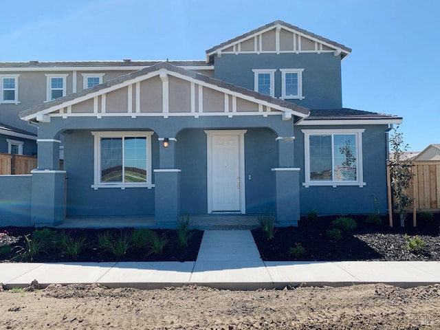 view of front of house with fence, stucco siding, and a porch
