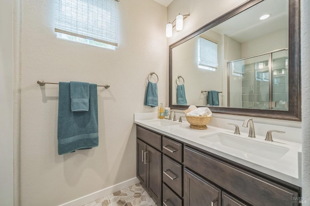 full bath featuring an enclosed shower, double vanity, baseboards, and a sink
