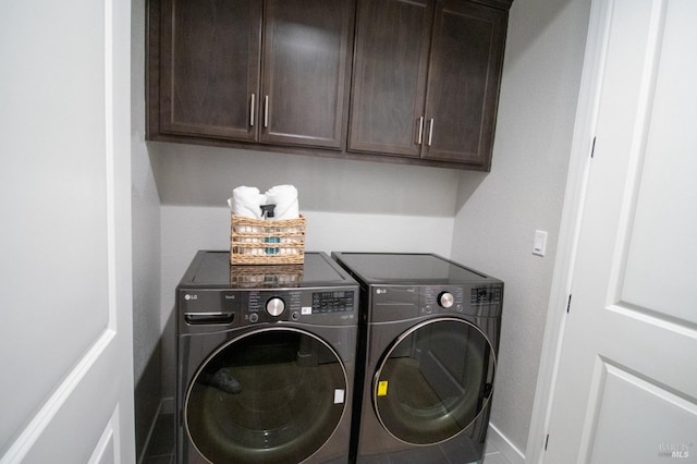 laundry area with washing machine and clothes dryer, baseboards, and cabinet space