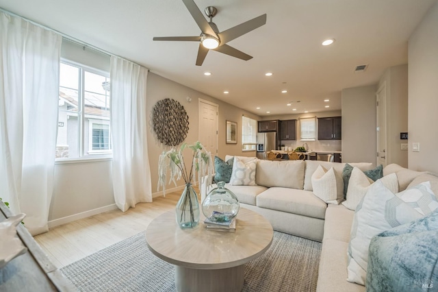 living area with light wood finished floors, a ceiling fan, baseboards, recessed lighting, and visible vents