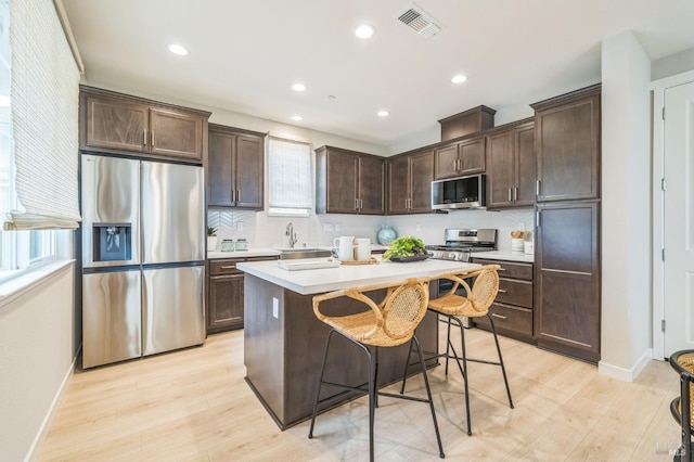 kitchen featuring light wood-style floors, light countertops, appliances with stainless steel finishes, and dark brown cabinetry