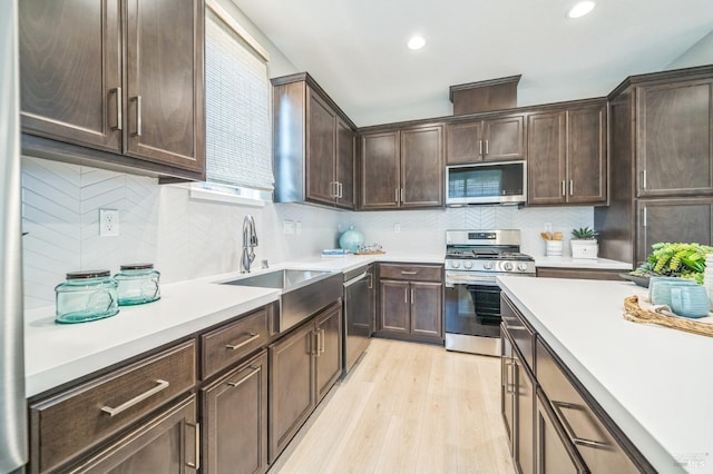 kitchen with light countertops, stainless steel appliances, a sink, and light wood-style flooring