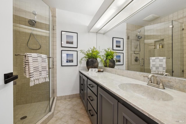 full bath with baseboards, vanity, tile patterned floors, and a stall shower
