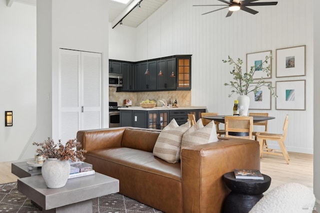 living room featuring light wood-type flooring, high vaulted ceiling, and ceiling fan