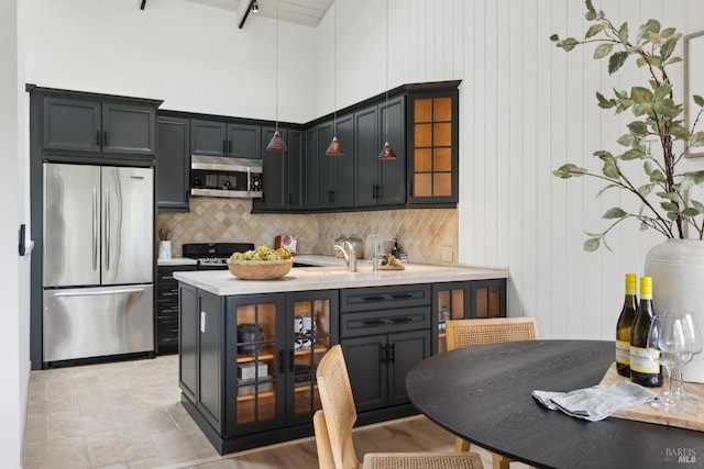 kitchen with stainless steel appliances, backsplash, glass insert cabinets, pendant lighting, and light countertops