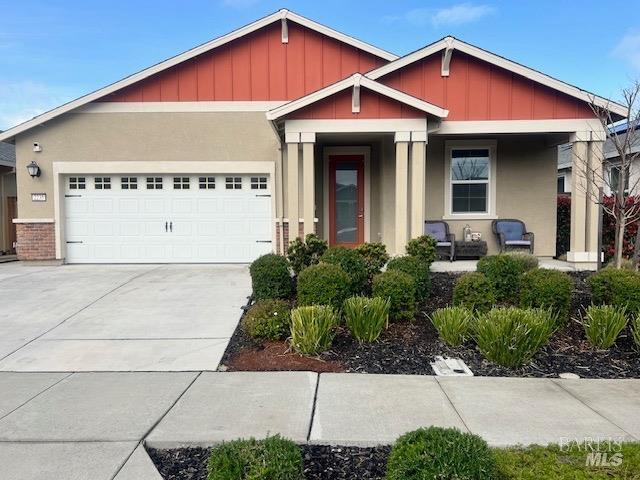 view of front of property featuring driveway, covered porch, stucco siding, an attached garage, and board and batten siding