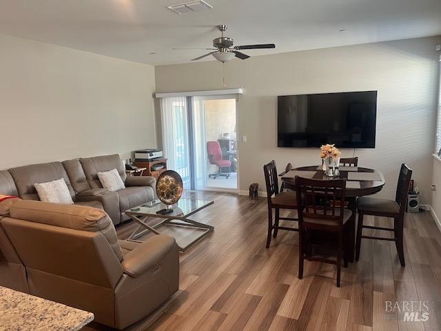 living room with baseboards, visible vents, a ceiling fan, and wood finished floors