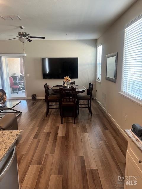 dining area featuring a ceiling fan, visible vents, baseboards, and wood finished floors