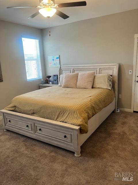 bedroom with baseboards, dark carpet, and a ceiling fan