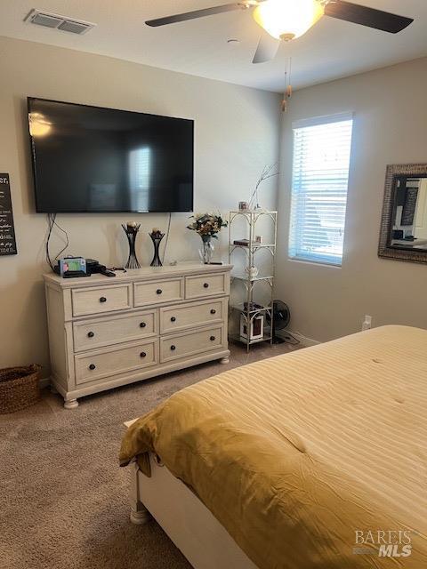 carpeted bedroom with ceiling fan and visible vents