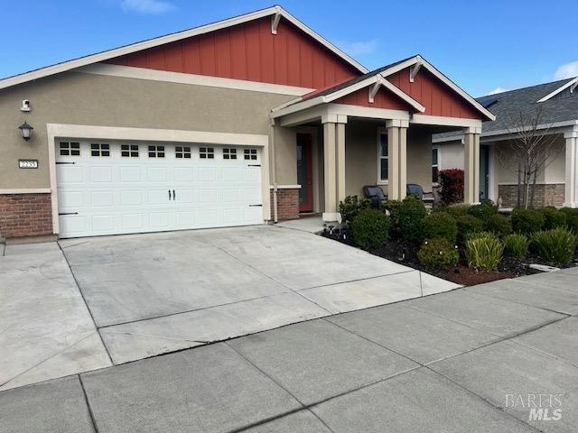 view of front of property with stucco siding, an attached garage, concrete driveway, and board and batten siding