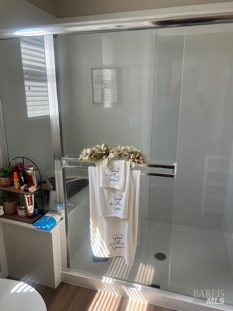full bath featuring toilet, a shower stall, and wood finished floors