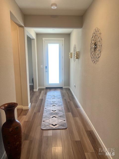 doorway to outside featuring baseboards and wood finished floors
