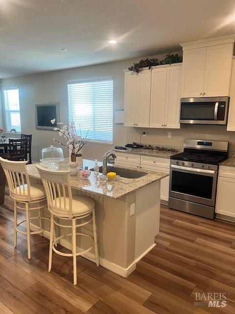 kitchen with white cabinetry, a sink, appliances with stainless steel finishes, and dark wood finished floors