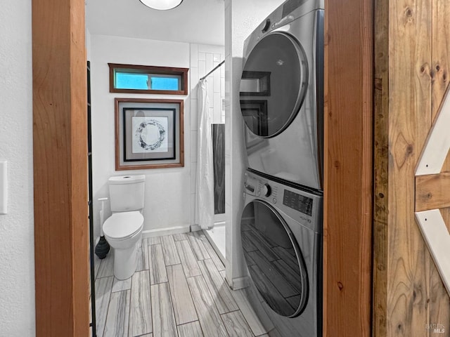 laundry area featuring laundry area, baseboards, and stacked washer and clothes dryer
