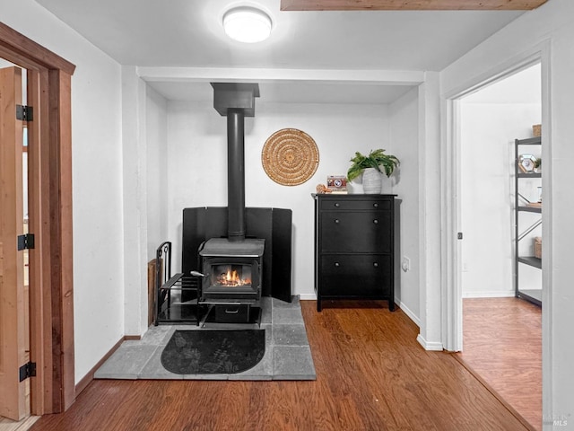 sitting room featuring baseboards, a wood stove, and wood finished floors