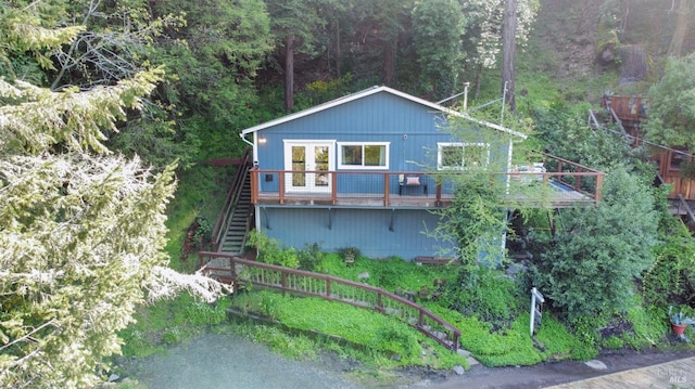 view of front facade with stairway, a view of trees, and a wooden deck