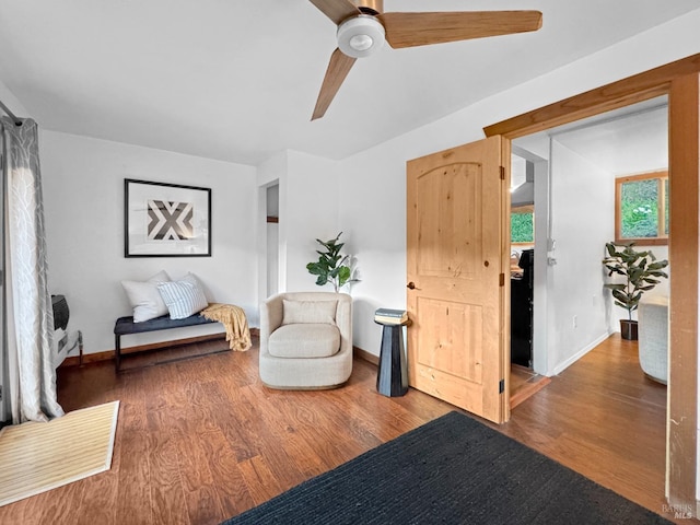 living area with a ceiling fan, baseboards, and wood finished floors
