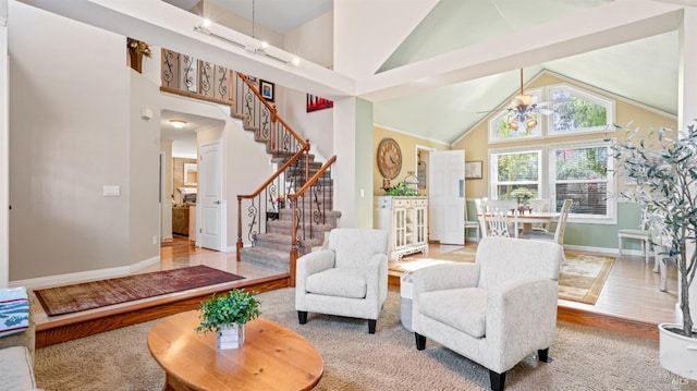 living room with a ceiling fan, baseboards, high vaulted ceiling, wood finished floors, and stairway