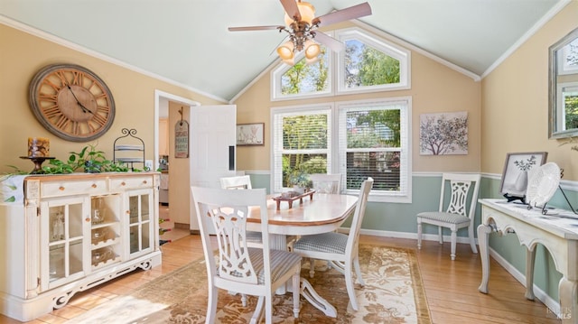 dining room featuring lofted ceiling, a ceiling fan, crown molding, a wainscoted wall, and light wood-type flooring