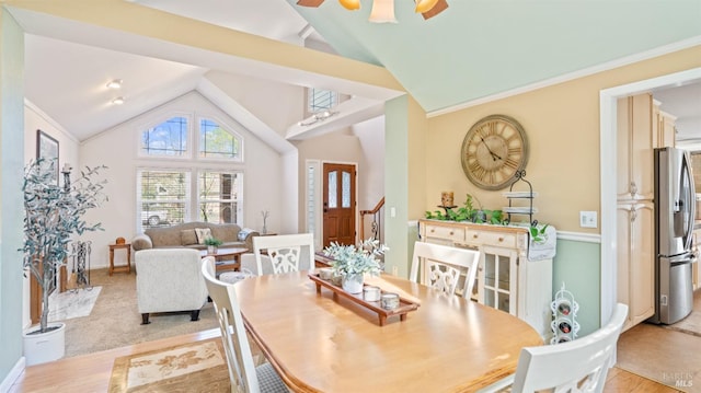 dining space featuring vaulted ceiling, crown molding, baseboards, and light wood-style floors