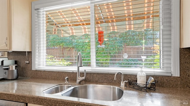 kitchen with a sink, stone counters, a wealth of natural light, and backsplash