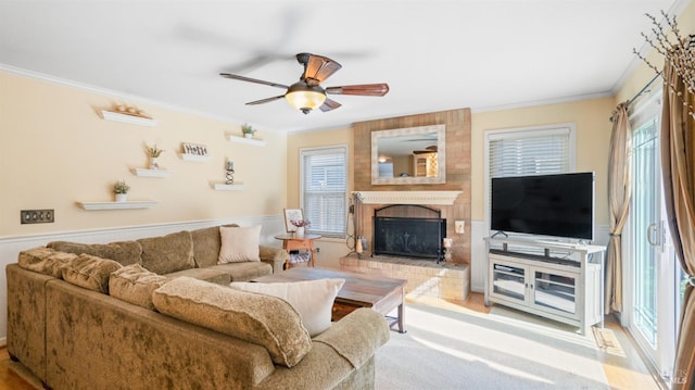 living area with ornamental molding, a healthy amount of sunlight, a fireplace, and ceiling fan