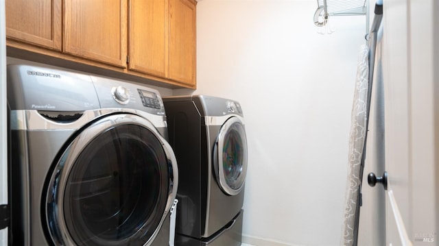 laundry room featuring baseboards, separate washer and dryer, and cabinet space